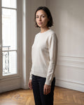 Pull femme col rond, coloris écru, porté dans un intérieur haussmannien parisien